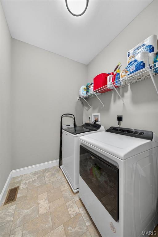 231 Flint Brook Dr, Ofallon, MO 63366 - laundry room featuring washer and clothes dryer and stone tile floors