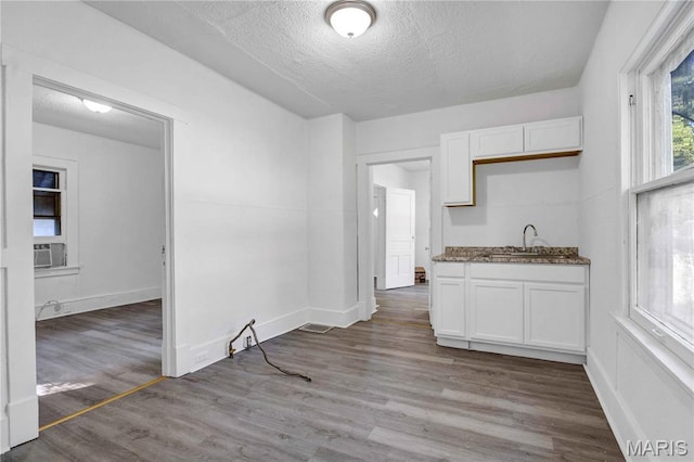 5316 Janet Ave, Jennings, MO 63136 - kitchen with white cabinets, a textured ceiling, wood finished floors, dark stone countertops, and cooling unit