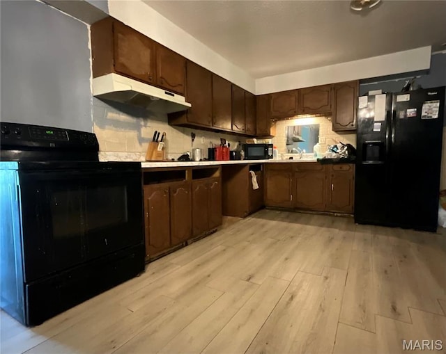 321 Walker St, Licking, MO 65542 - kitchen featuring black appliances, under cabinet range hood, light wood-type flooring, decorative backsplash, and dark brown cabinets