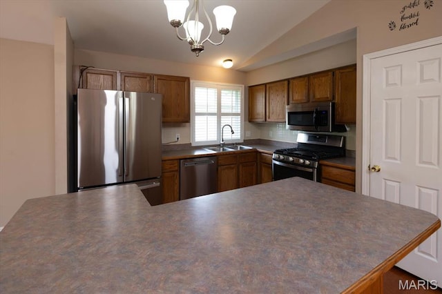 1715 Foxglove Dr, Saint Charles, MO 63303 - kitchen with stainless steel appliances, vaulted ceiling, dark countertops, a chandelier, and brown cabinetry