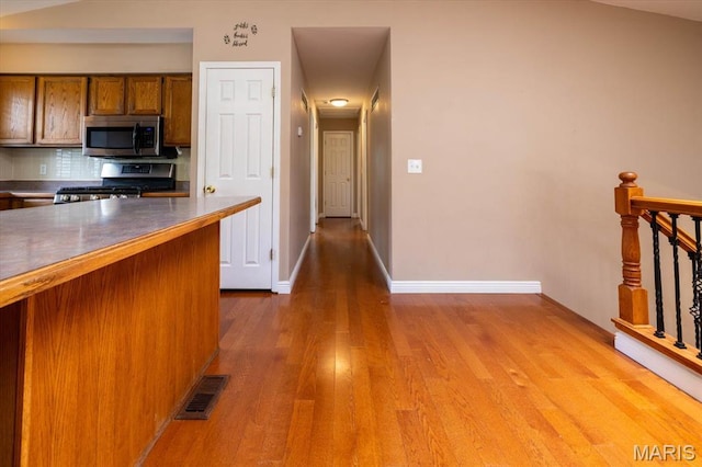 1715 Foxglove Dr, Saint Charles, MO 63303 - kitchen featuring appliances with stainless steel finishes, wood finished floors, tasteful backsplash, and brown cabinetry