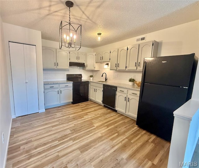 601 N Monroe St Unit 9, Pacific, MO 63069 - kitchen with black appliances, under cabinet range hood, light wood-type flooring, light countertops, and a chandelier