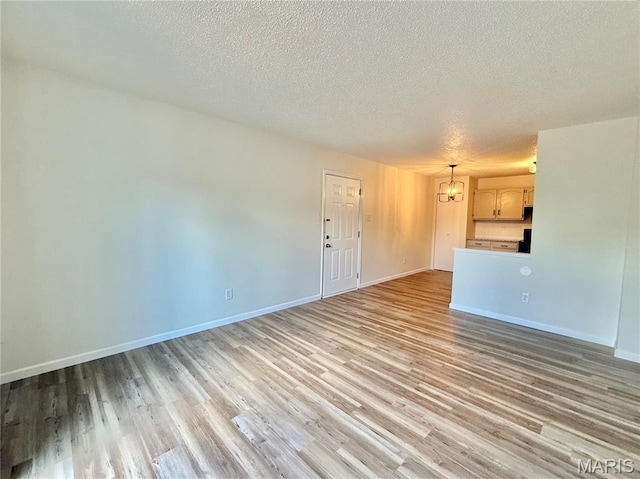 601 N Monroe St Unit 9, Pacific, MO 63069 - unfurnished living room featuring a chandelier, a textured ceiling, and light wood-style flooring