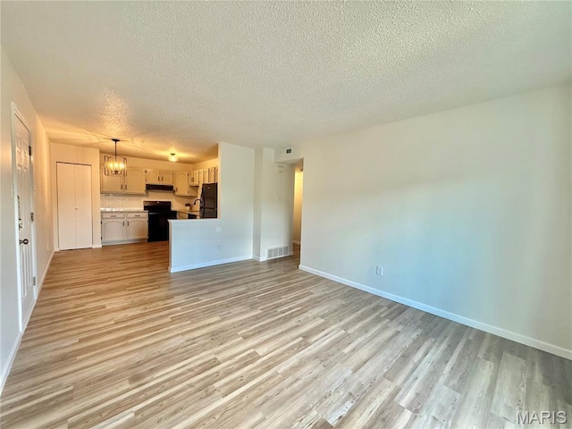 601 N Monroe St Unit 9, Pacific, MO 63069 - unfurnished living room featuring a textured ceiling, light wood-style floors, and a chandelier