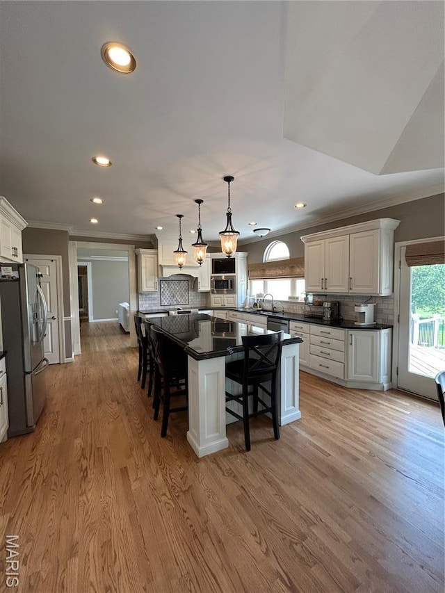 kitchen featuring appliances with stainless steel finishes, ornamental molding, dark countertops, a kitchen bar, and backsplash