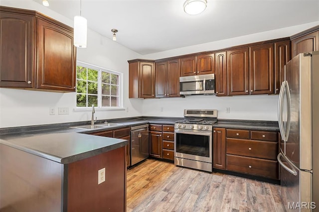 104 Miller Dr, Fenton, MO 63026 - kitchen featuring appliances with stainless steel finishes, dark countertops, light wood finished floors, a peninsula, and decorative light fixtures