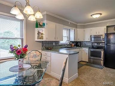 4840 S Point Rd, Washington, MO 63090 - kitchen featuring appliances with stainless steel finishes, a peninsula, tasteful backsplash, a chandelier, and white cabinets