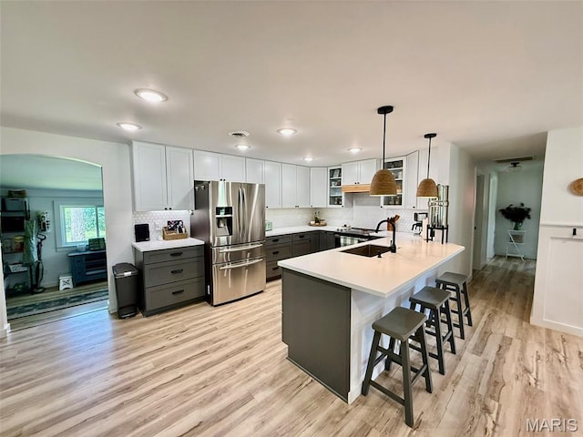 10107 Cannon Mines Rd, Cadet, MO 63630 - kitchen featuring stainless steel fridge, a peninsula, arched walkways, a kitchen bar, and light wood-type flooring