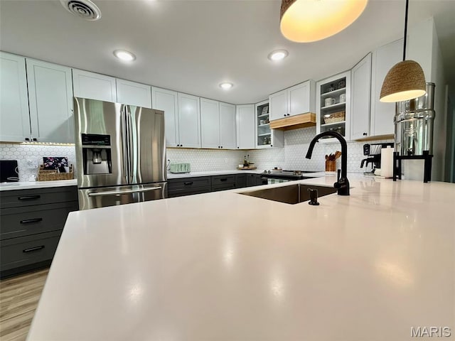 10107 Cannon Mines Rd, Cadet, MO 63630 - kitchen with stainless steel fridge, glass insert cabinets, backsplash, light countertops, and recessed lighting