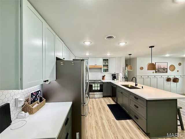 10107 Cannon Mines Rd, Cadet, MO 63630 - kitchen with stainless steel appliances, a peninsula, decorative backsplash, a kitchen bar, and light wood finished floors