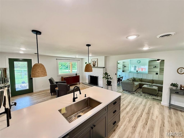 10107 Cannon Mines Rd, Cadet, MO 63630 - kitchen with open floor plan, light wood-type flooring, a fireplace, light countertops, and decorative light fixtures