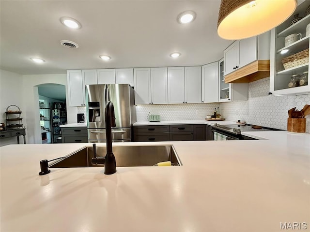 10107 Cannon Mines Rd, Cadet, MO 63630 - kitchen featuring stainless steel fridge, arched walkways, light countertops, glass insert cabinets, and decorative backsplash