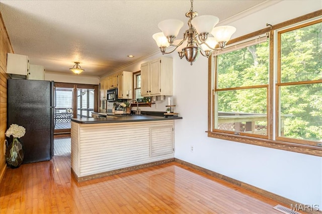 25 Whispering Oaks Dr, Washington, MO 63090 - kitchen with black appliances, dark countertops, a chandelier, a peninsula, and wood-type flooring
