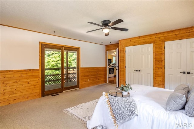 25 Whispering Oaks Dr, Washington, MO 63090 - carpeted bedroom featuring wooden walls, wainscoting, access to exterior, multiple closets, and ceiling fan