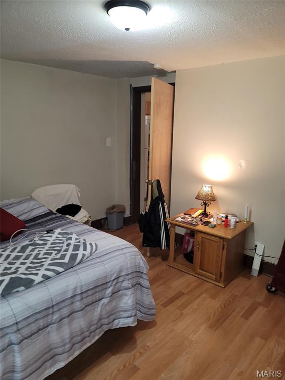 4833 Penrose St, Saint Louis, MO 63115 - bedroom with light wood-style floors, a textured ceiling, and a closet