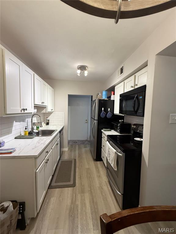 670 Coeur De Royale Dr Unit A, Creve Coeur, MO 63141 - kitchen with stainless steel appliances, light wood-style flooring, decorative backsplash, white cabinetry, and light countertops