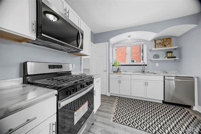 6629 Barken Ave, Northwoods, MO 63121 - kitchen featuring appliances with stainless steel finishes, white cabinets, light wood-style flooring, open shelves, and light stone countertops