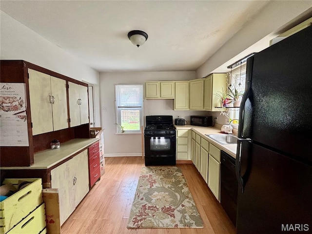 5540 Arthur Ave, Saint Louis, MO 63139 - kitchen featuring black appliances, light countertops, light wood-style floors, and cream cabinets