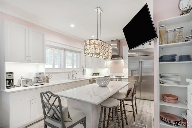 354 Frieda Ave, Kirkwood, MO 63122 - kitchen with wall chimney exhaust hood, stainless steel appliances, a kitchen breakfast bar, white cabinets, and a center island