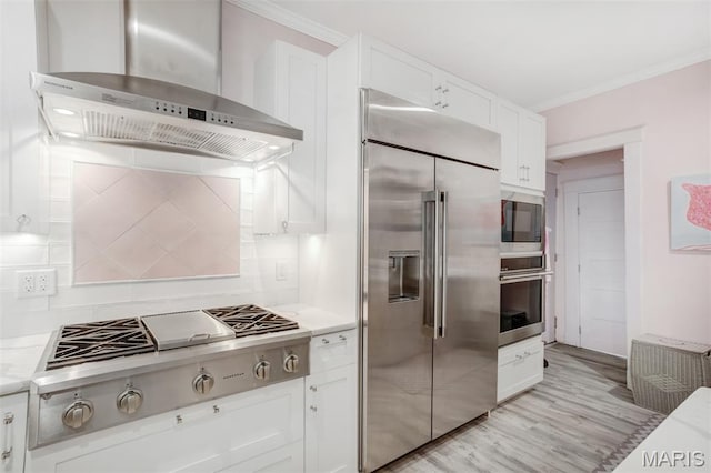 354 Frieda Ave, Kirkwood, MO 63122 - kitchen featuring wall chimney exhaust hood, built in appliances, ornamental molding, white cabinets, and tasteful backsplash