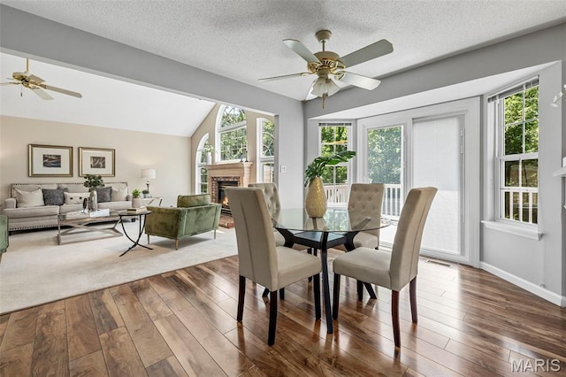 3164 Willow Bend Dr, Saint Charles, MO 63303 - dining room with a ceiling fan, wood-type flooring, a brick fireplace, lofted ceiling, and a textured ceiling