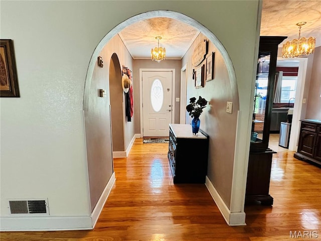 202 Maple, Licking, MO 65542 - entryway featuring a chandelier, light wood-type flooring, arched walkways, and ornamental molding