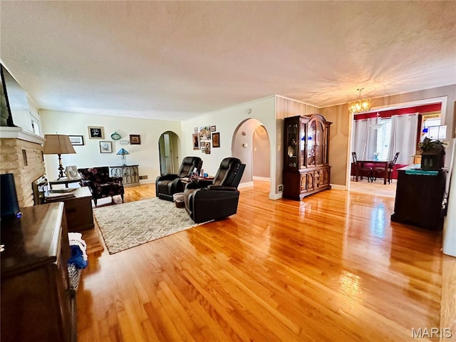 202 Maple, Licking, MO 65542 - living room featuring arched walkways, a chandelier, light wood-style floors, and a fireplace