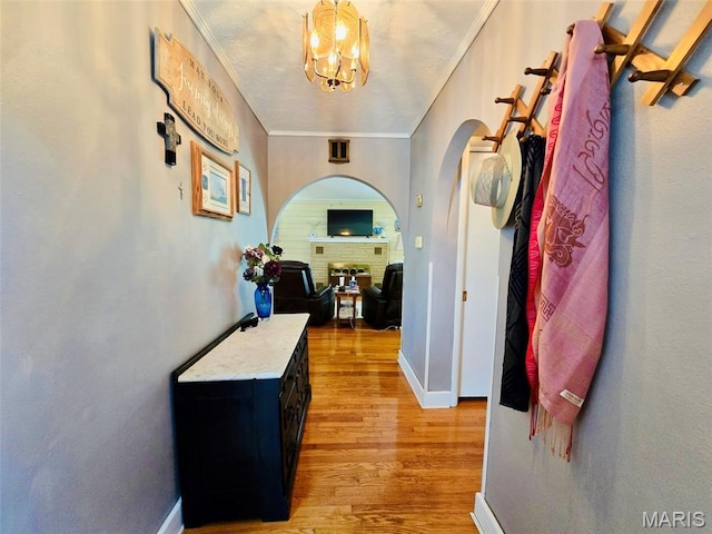 202 Maple, Licking, MO 65542 - corridor with light wood-type flooring, arched walkways, crown molding, and a chandelier
