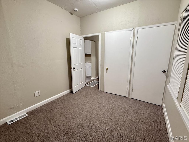 4652 Shirley Pl, Saint Louis, MO 63115 - unfurnished bedroom featuring carpet flooring, a textured wall, and two closets