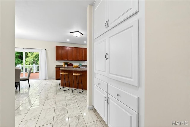 334 Lauren Lndg, Ballwin, MO 63021 - kitchen with light marble finish floors, recessed lighting, a breakfast bar, dark countertops, and white cabinets
