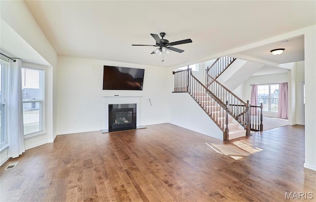 17603 Hitching Post Ct, Eureka, MO 63025 - unfurnished living room featuring stairs, wood finished floors, ceiling fan, and a glass covered fireplace