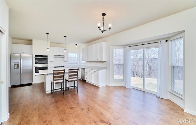 17603 Hitching Post Ct, Eureka, MO 63025 - kitchen with stainless steel appliances, a breakfast bar area, light countertops, white cabinetry, and a kitchen island