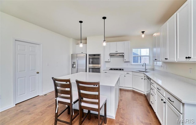 17603 Hitching Post Ct, Eureka, MO 63025 - kitchen featuring stainless steel appliances, under cabinet range hood, wood finished floors, and white cabinets