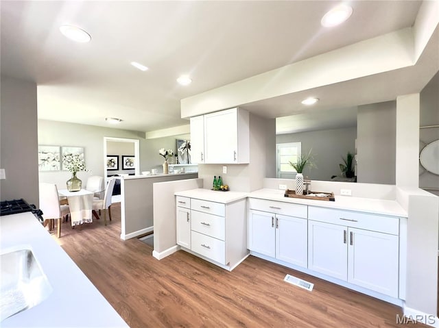 1248 Lynchester Ln, Kirkwood, MO 63122 - kitchen featuring a peninsula, light countertops, white cabinetry, light wood-type flooring, and recessed lighting