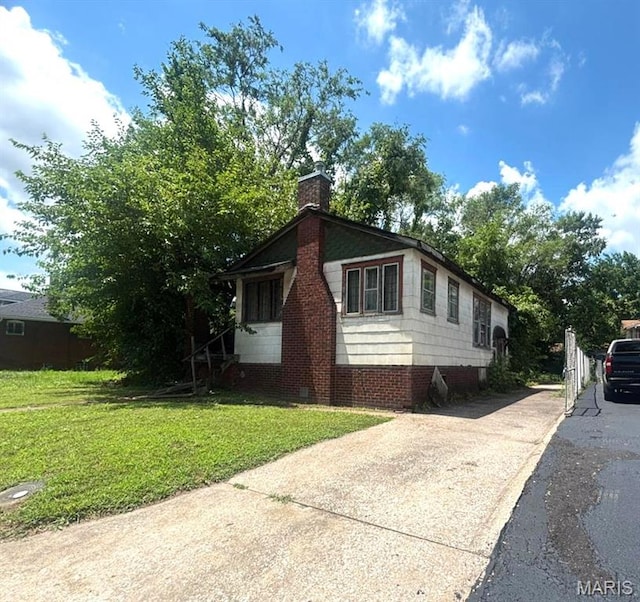 1625 N 46th St E, St Louis, IL 62204 - view of home's exterior with concrete driveway, a lawn, and a chimney