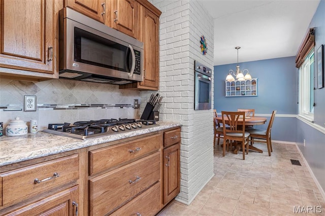 5028 Baldcypress Ct, Saint Louis, MO 63128 - kitchen with stainless steel appliances, tasteful backsplash, brown cabinetry, a chandelier, and pendant lighting