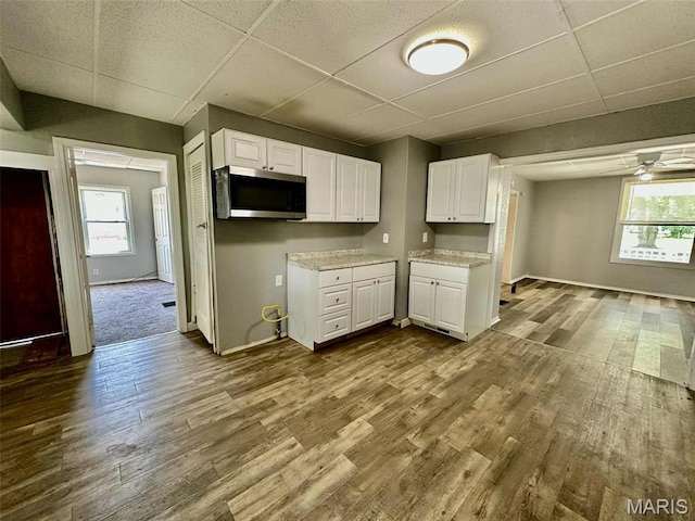 316 Church St, East Alton, IL 62024 - kitchen featuring stainless steel microwave, dark wood-style flooring, a paneled ceiling, white cabinets, and light countertops