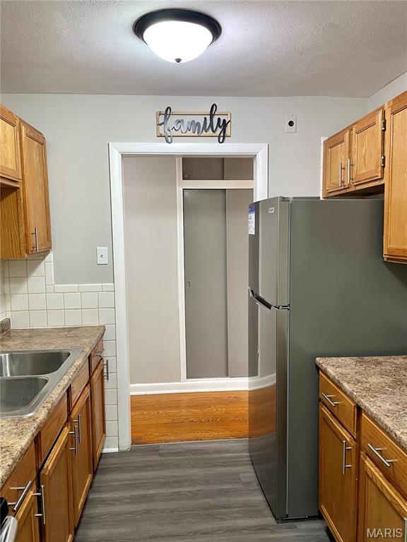 9264 Bellefontaine Rd, Bellefontaine Nghbrs, MO 63137 - kitchen with dark wood-style floors, freestanding refrigerator, a textured ceiling, brown cabinetry, and light countertops