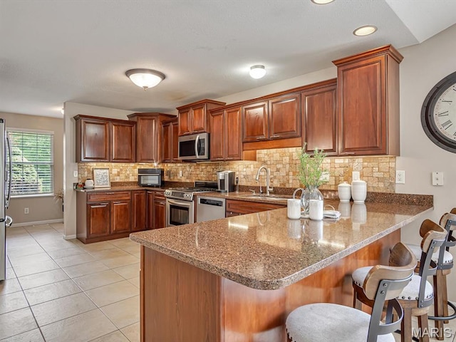 22 Foxmoor Dr, Maryville, IL 62062 - kitchen featuring stainless steel appliances, a peninsula, decorative backsplash, and a kitchen bar