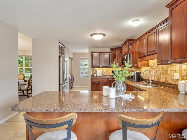 22 Foxmoor Dr, Maryville, IL 62062 - kitchen featuring appliances with stainless steel finishes, a peninsula, tasteful backsplash, a kitchen bar, and light stone countertops