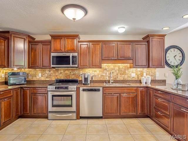 22 Foxmoor Dr, Maryville, IL 62062 - kitchen featuring stainless steel appliances, backsplash, a textured ceiling, dark stone counters, and light tile patterned floors