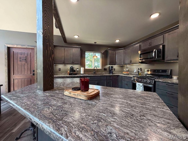 10185 Springer Dr, Bonne Terre, MO 63628 - kitchen featuring stainless steel appliances, a breakfast bar, dark stone counters, dark brown cabinets, and recessed lighting