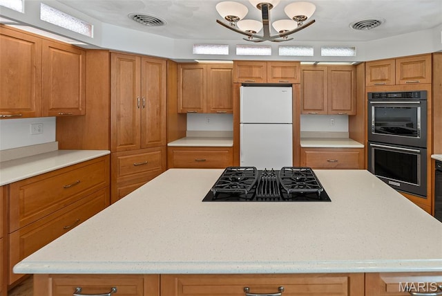46 Coronation Dr, Millstadt, IL 62260 - kitchen featuring black appliances, brown cabinetry, a center island, a chandelier, and light stone counters
