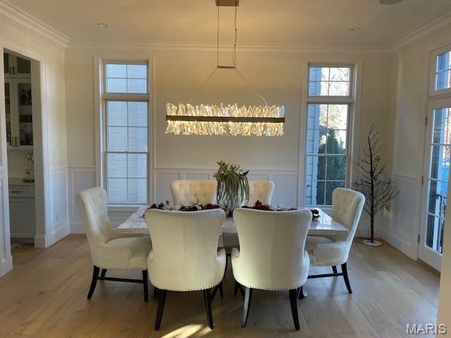 8145 University Dr, Clayton, MO 63105 - dining area featuring a decorative wall, light wood-type flooring, crown molding, and wainscoting