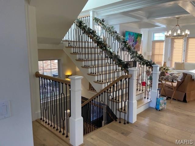 8145 University Dr, Clayton, MO 63105 - staircase featuring wood finished floors, a chandelier, healthy amount of natural light, coffered ceiling, and beam ceiling