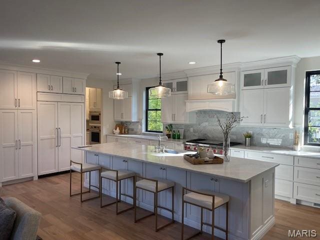 8145 University Dr, Clayton, MO 63105 - kitchen with paneled refrigerator, white cabinetry, a breakfast bar area, wood finished floors, and recessed lighting