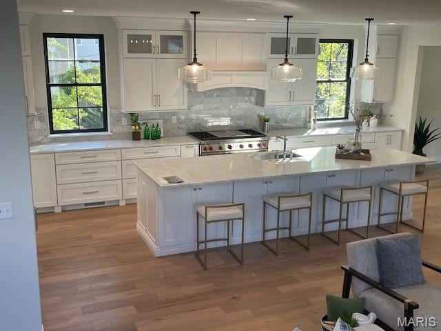 8145 University Dr, Clayton, MO 63105 - kitchen featuring custom exhaust hood, light wood-style flooring, stove, a breakfast bar area, and white cabinetry
