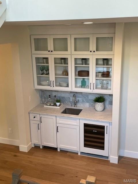 8145 University Dr, Clayton, MO 63105 - indoor wet bar with wine cooler, decorative backsplash, and light wood-style floors