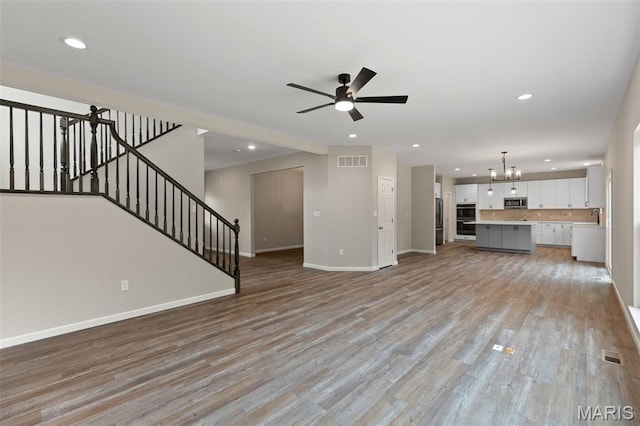 2213 Rule Ave, Maryland Heights, MO 63146 - unfurnished living room with a chandelier, recessed lighting, light wood-style floors, a ceiling fan, and stairs