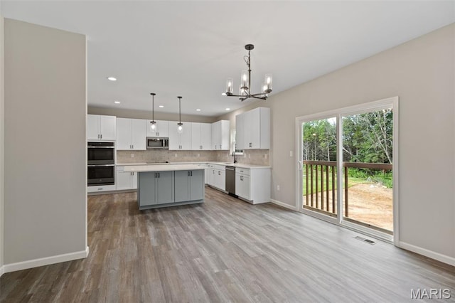2213 Rule Ave, Maryland Heights, MO 63146 - kitchen featuring stainless steel appliances, light countertops, a chandelier, white cabinetry, and backsplash